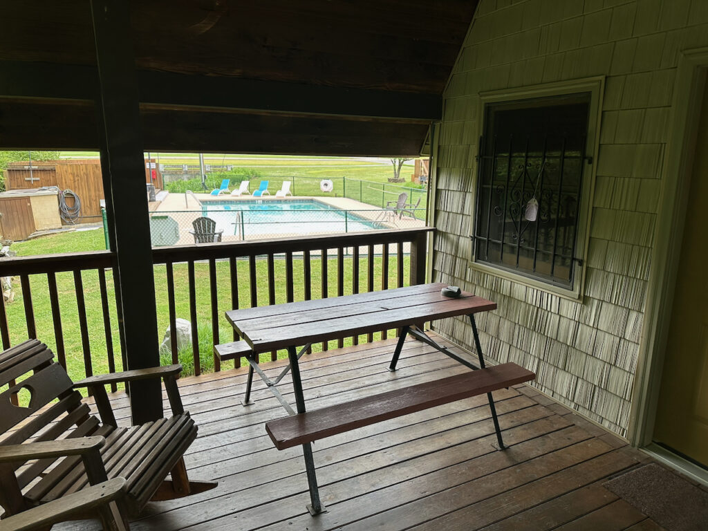 cabin 21 porch with pool in the background and picnic table on the porch