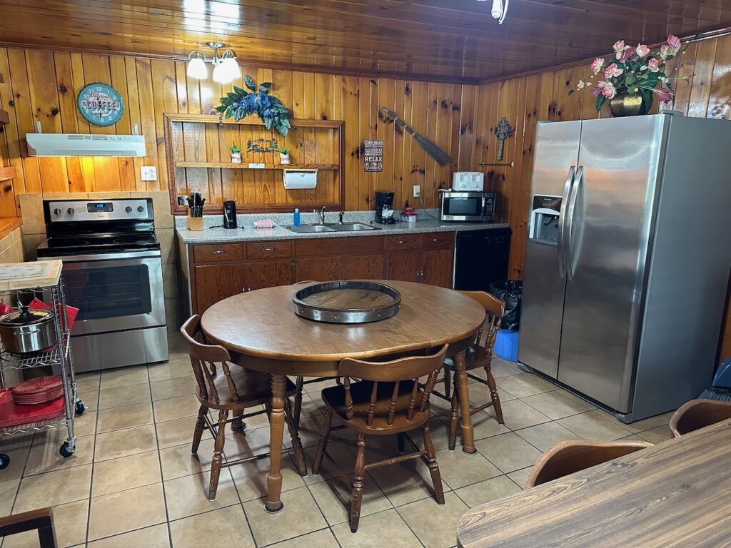 Full kitchen of heritage cabin showing dining room table, refirigerator, stove, counter tops