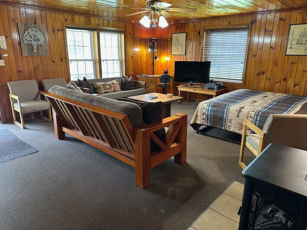 The living space in Cabin 15 with king bed, 2 couches, tv and coffee table