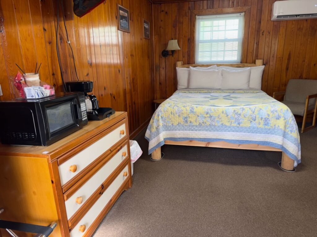 queen sized bed in roomo 12 at docks motel with dresser in forreground